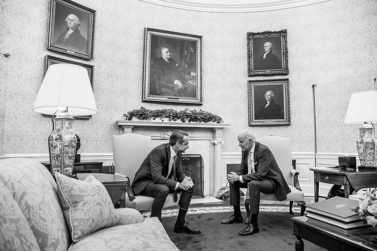 Kyriakos Mitsotakis and Joe Biden seated and talking in a formal room.