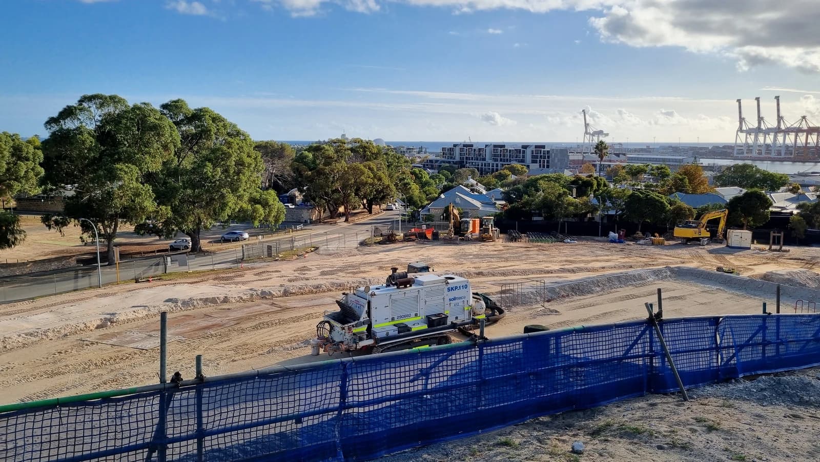 A construction site on Burt Street with earthmoving equipment under a partly cloudy sky.