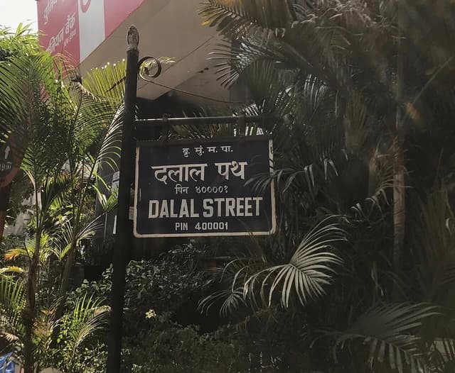 Street sign for Dalal Street in Mumbai, surrounded by green foliage.