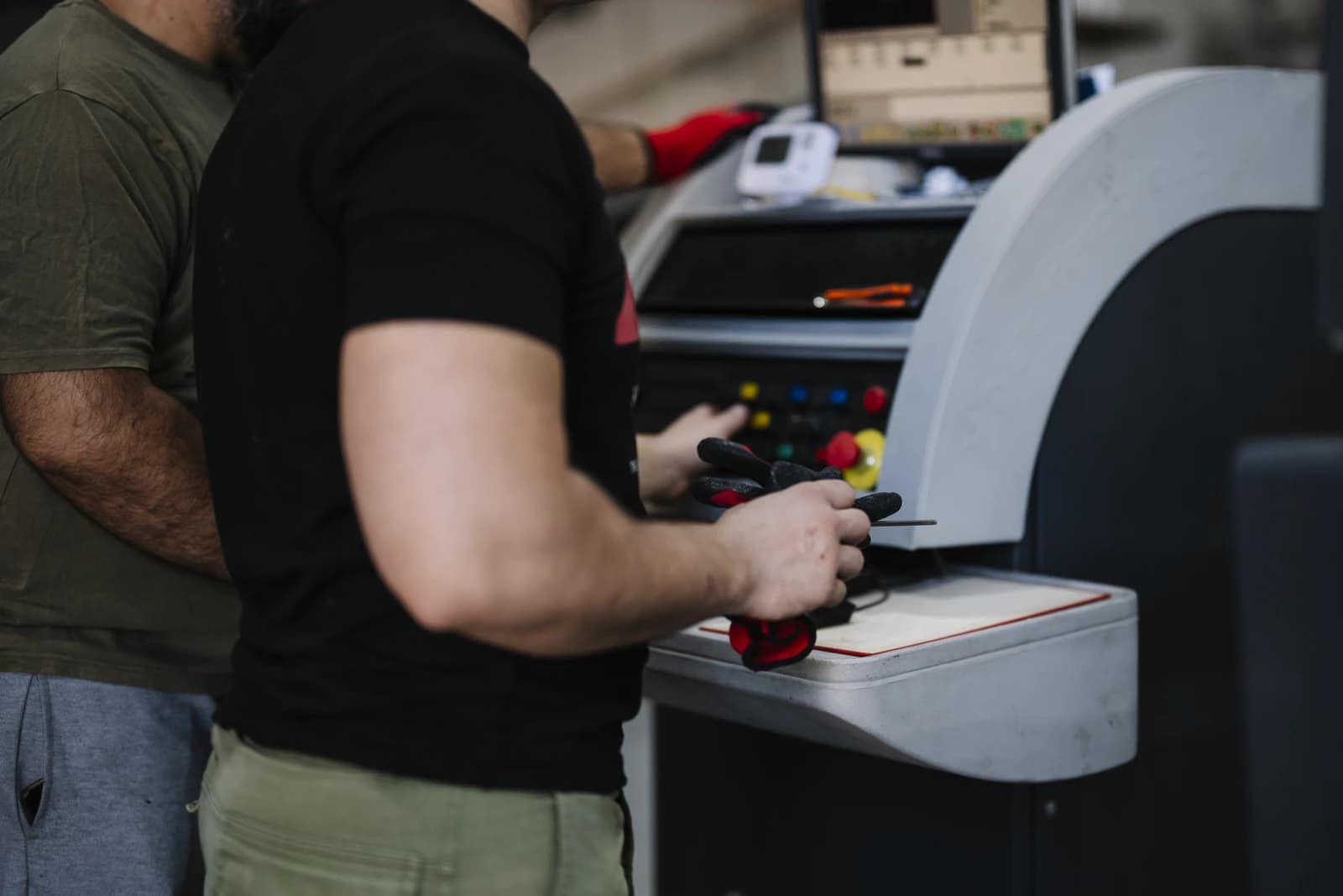 Two factory workers operating controls on an industrial machine.