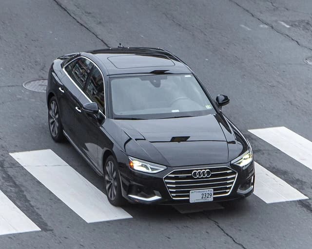Black Audi A4 (B9) sedan driving on a city street.