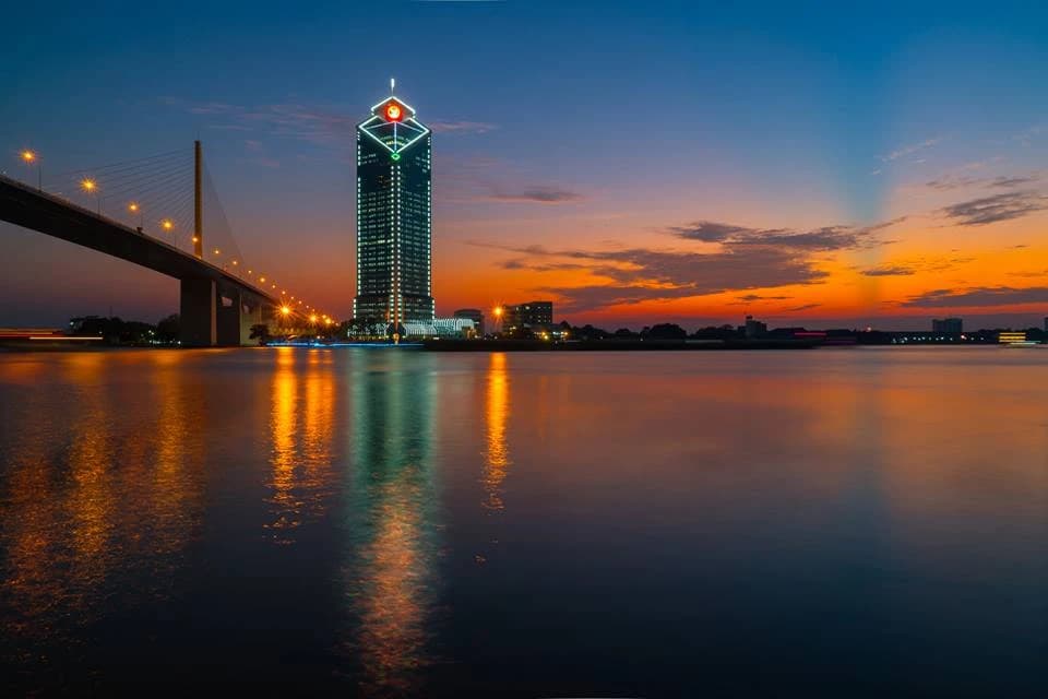 KBank Headquarters building in Bangkok, Thailand, at sunset next to a bridge.