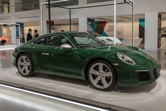 Green Porsche 911 luxury sports car on display in a showroom.