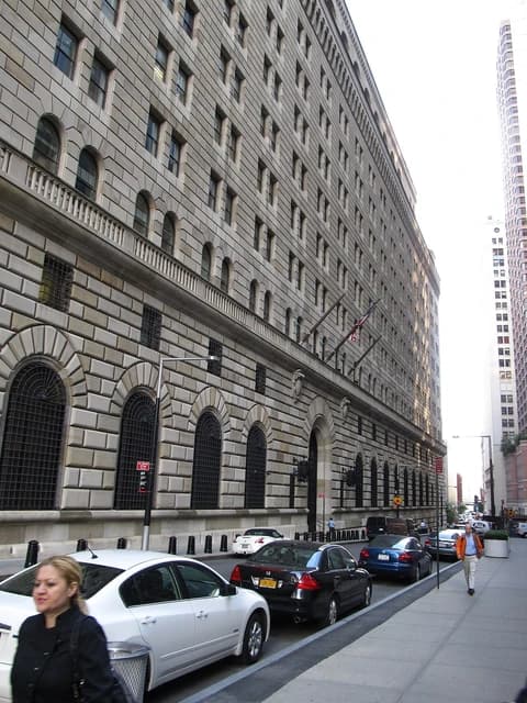 Federal Reserve Bank of New York, a large, historic stone building, viewed from a street.