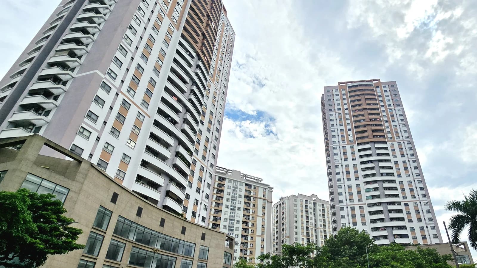 Modern apartment buildings with balconies against a cloudy sky in Hanoi.