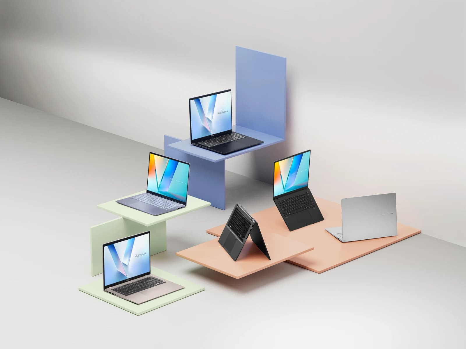 Several ASUS Vivobook laptops on display in a studio setting.