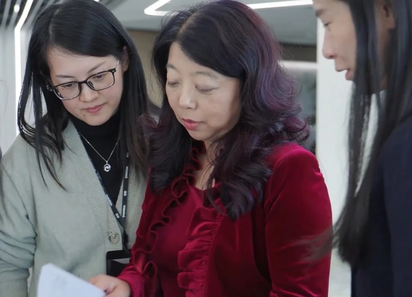 Deloitte China chairwoman Jiang Ying looking at documents with two individuals.