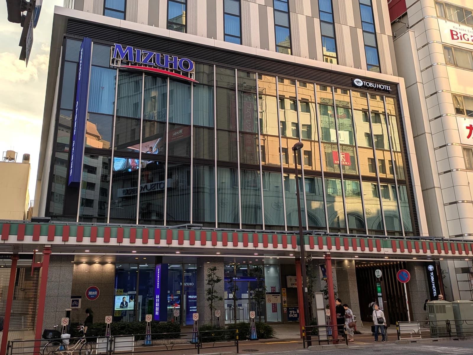 Exterior of Mizuho Bank Kaminarimon Branch building with street and people.
