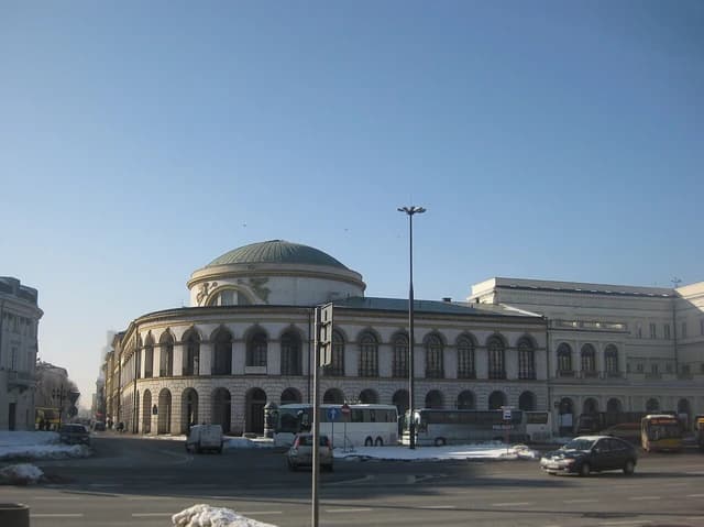 Bank Polski building, Warsaw, Poland, with cars and buses on a street.