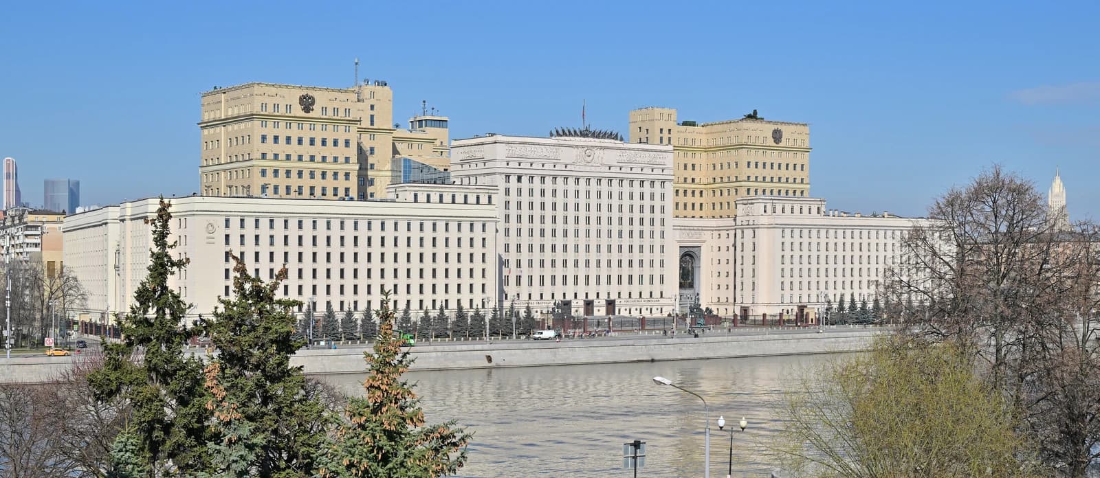 The Russian Ministry of Defense building in Moscow stands along a river under a clear sky.