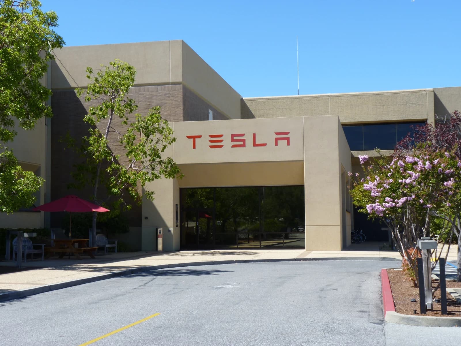 Exterior of Tesla Motors headquarters building with red Tesla logo above main entrance.