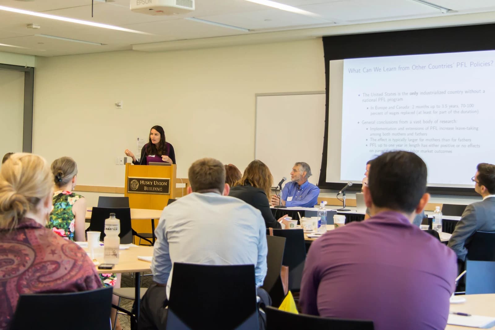 Woman giving a presentation on Paid Family Leave policies to an audience.