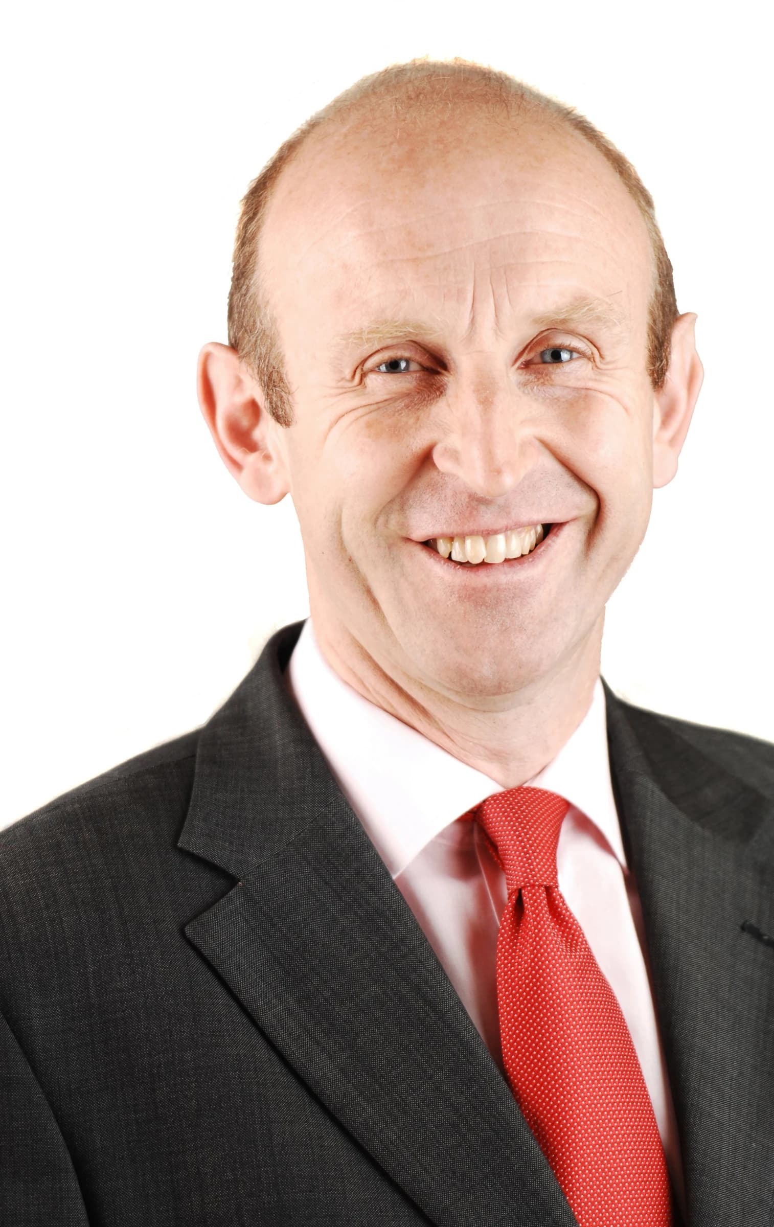 John Healey MP smiling in an official portrait with a white background.