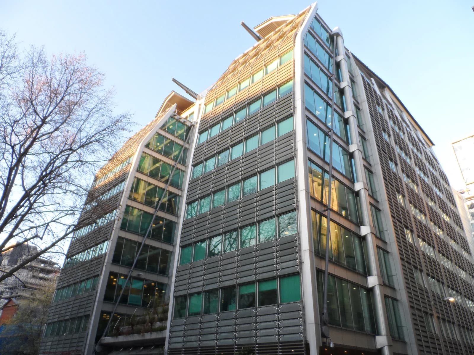 Modern building with glass and metallic facade against a clear sky.