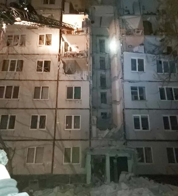 Damaged apartment building in Kharkiv showing collapsed sections and debris below.