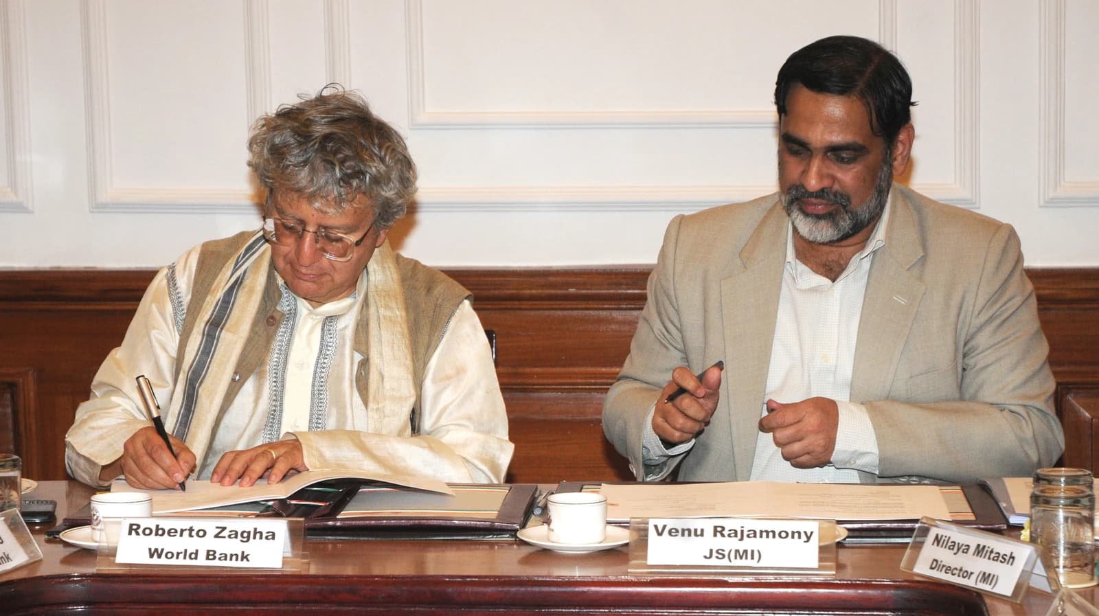 Venu Rajamony, Joint Secretary, and Roberto Zagha, World Bank, signing documents at a meeting.