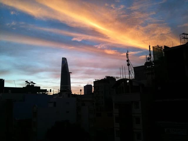 Ho Chi Minh City skyline with Bitexco Financial Tower silhouetted against a sunrise sky.