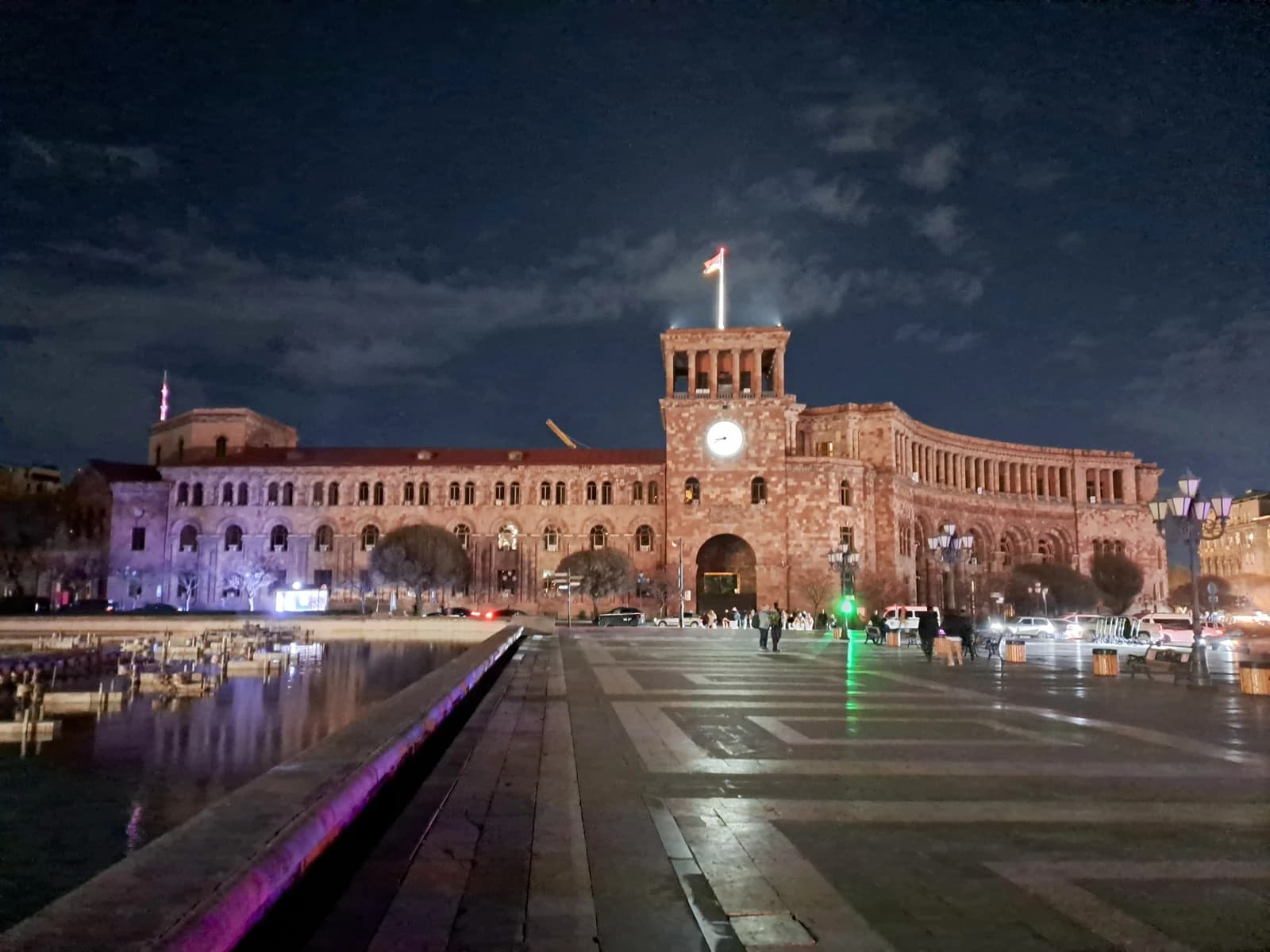 Yerevan Government building in Armenia at night, with streetlights and reflections in water.