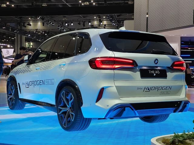 White BMW iX5 Hydrogen Fuel Cell vehicle on display indoors, rear view.
