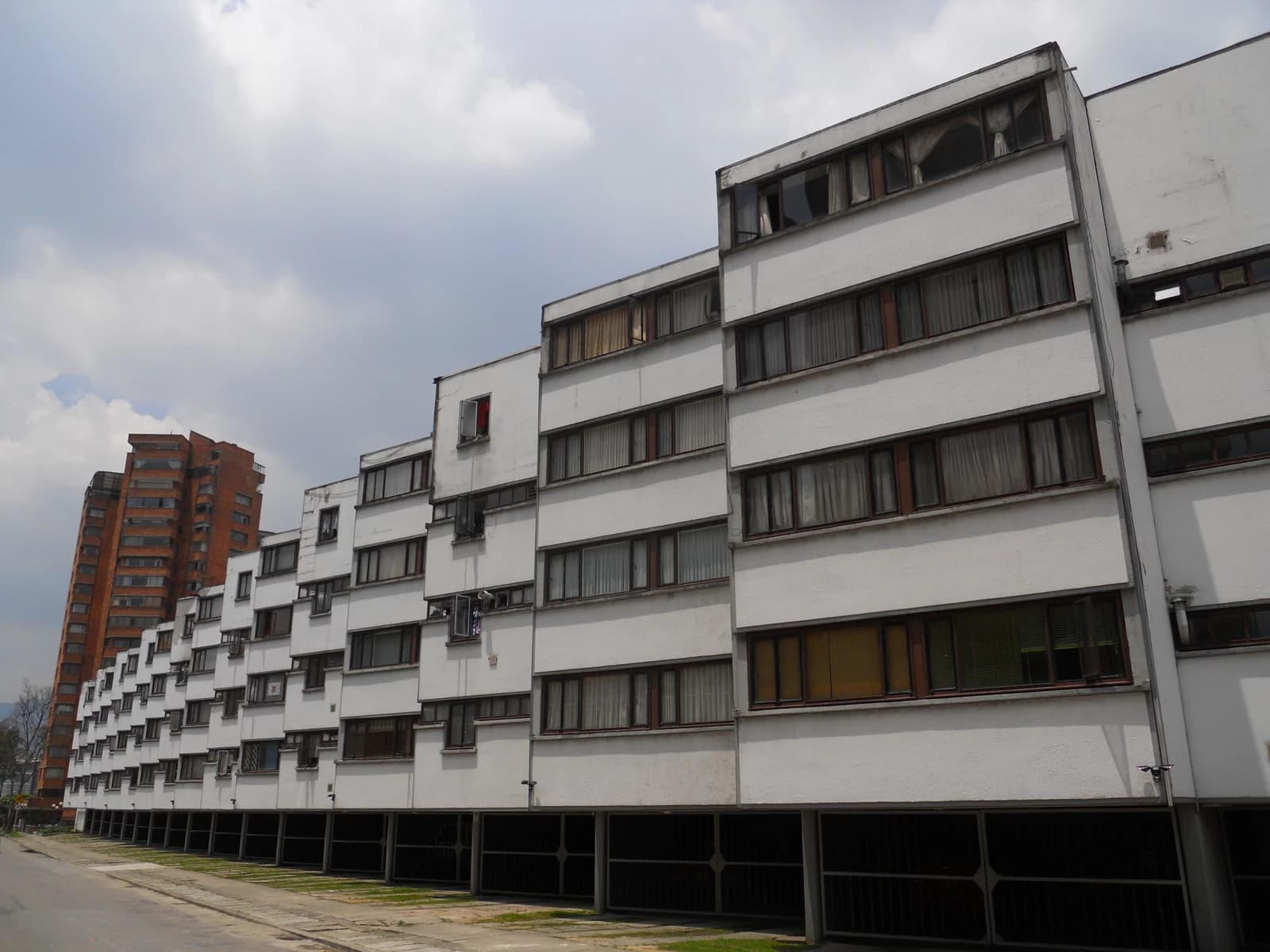 Apartment complex with multiple white buildings and a taller brick building in the background.