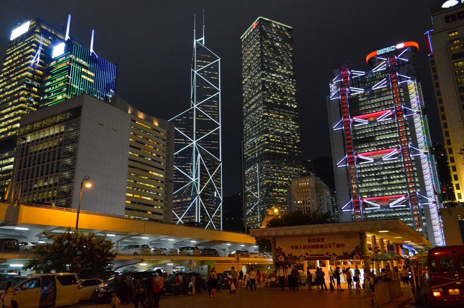 Illuminated skyscrapers including Bank of China Tower and HSBC Main Building at night in Hong Kong.