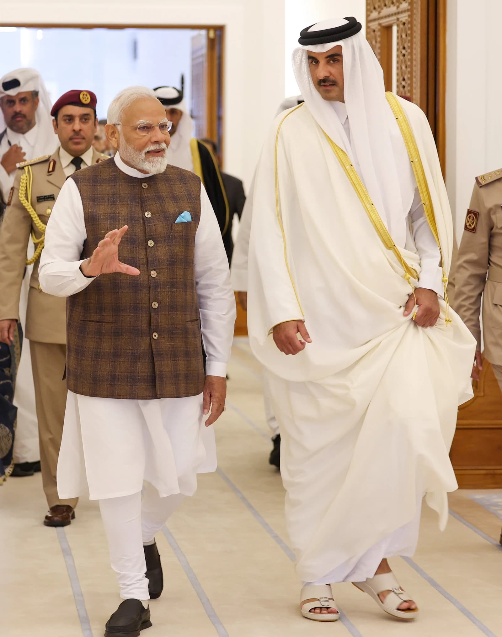 Indian Prime Minister Narendra Modi and Emir of Qatar Sheikh Tamim bin Hamad Al Thani walk together.