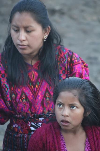 Indigenous woman and girl in traditional clothing at a market in Guatemala.