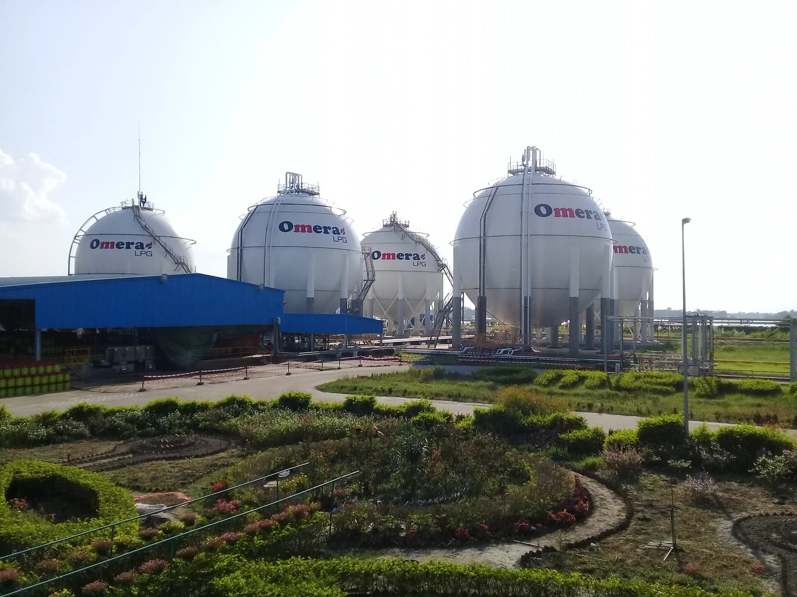 Several large white spherical storage tanks with "Omera LPG" branding in an industrial area.