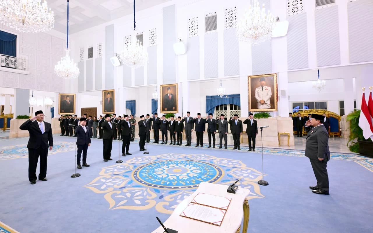 Government officials in suits and traditional caps saluting during a formal event.