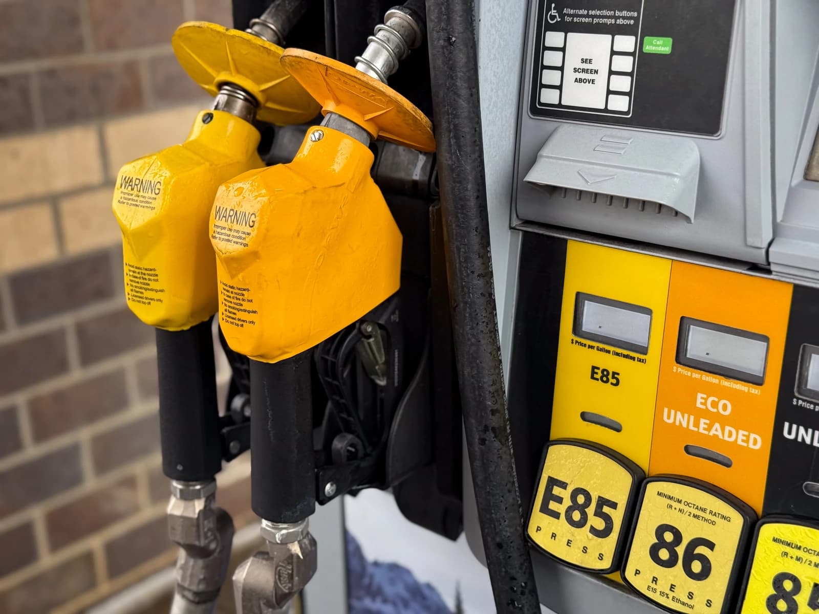 Close-up of a yellow gas pump with nozzles for E85 and Eco Unleaded fuel.