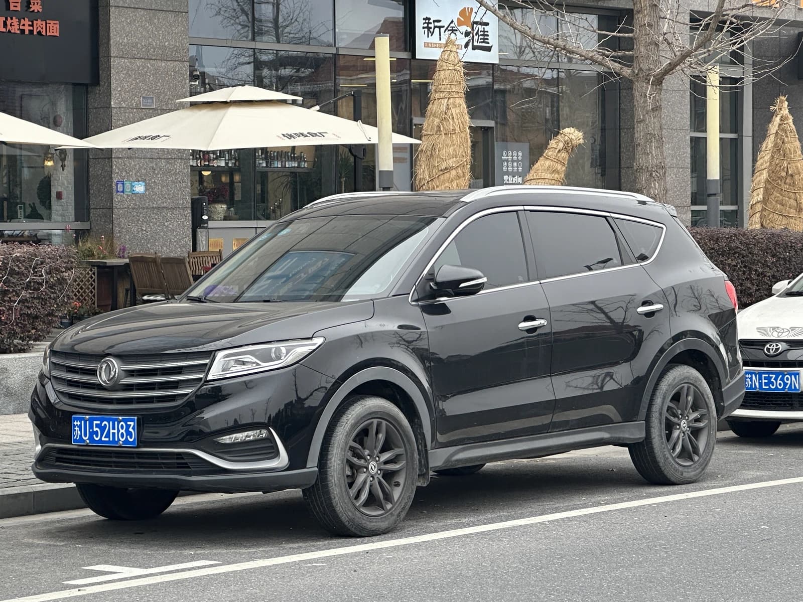 Black Fengon 580 facelift SUV parked on a city street in front of buildings.