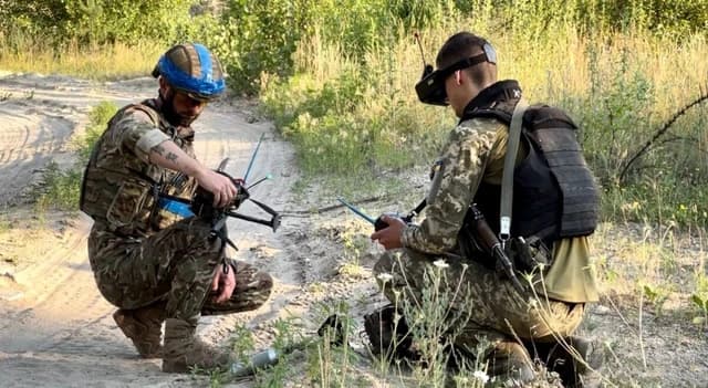 Two Ukrainian soldiers preparing an FPV drone for operation.