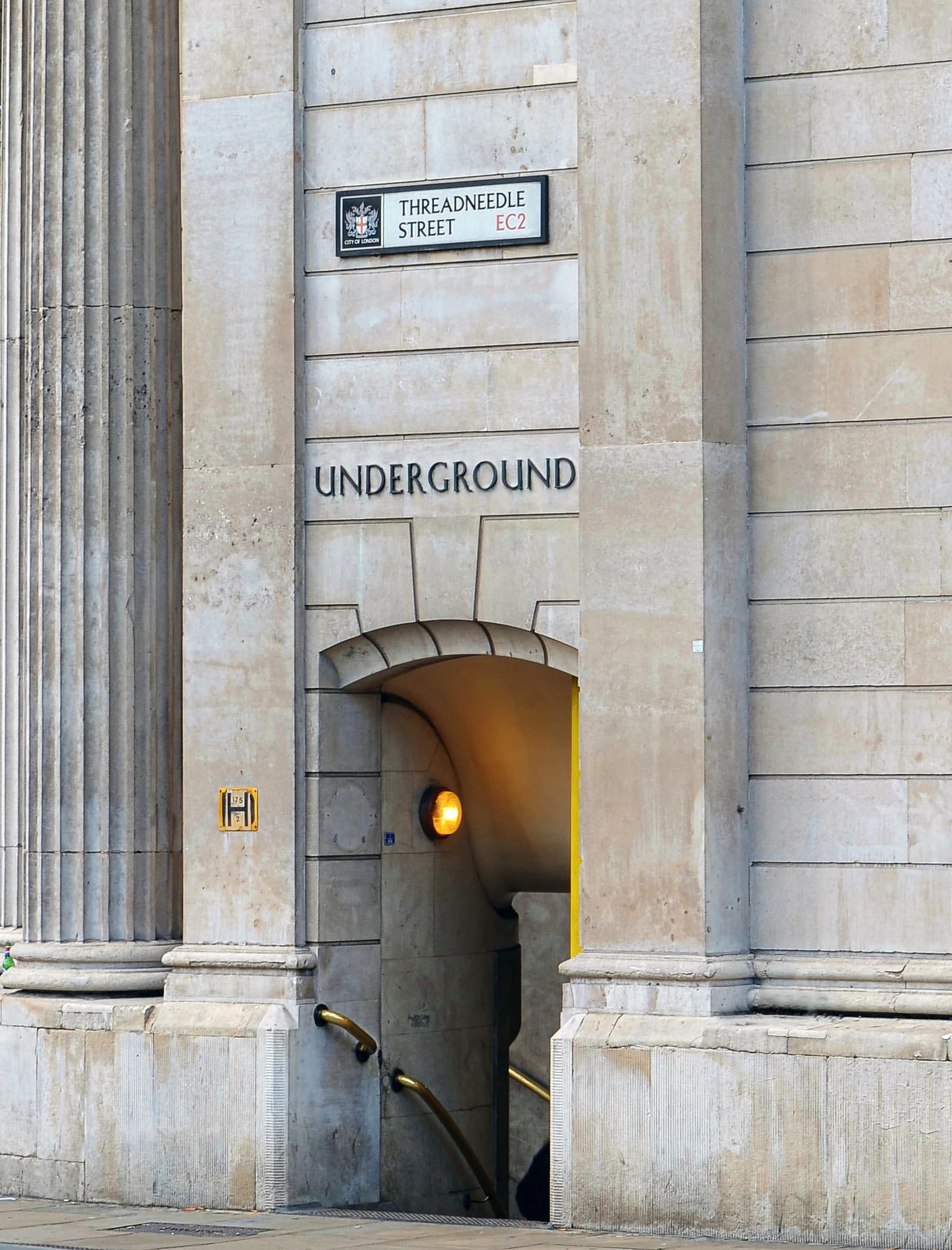 An underground entrance with a Threadneedle Street sign on a stone building in London.
