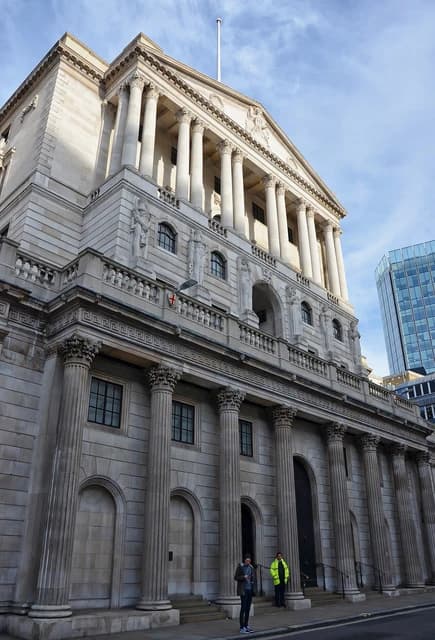 Bank of England building with large columns, seen from the street, with a modern building in the background.