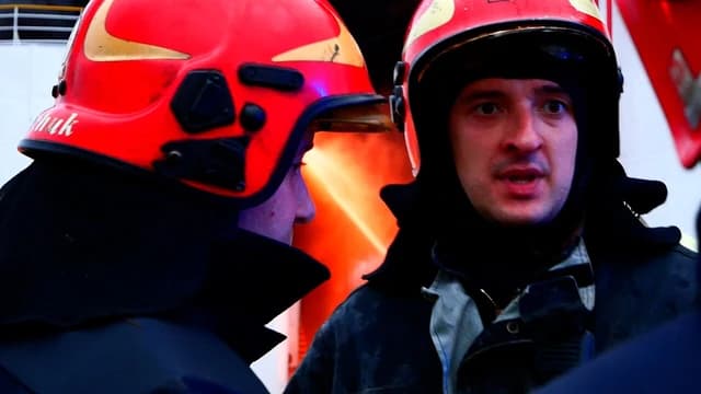 Two firefighters in red helmets looking at each other during an incident.
