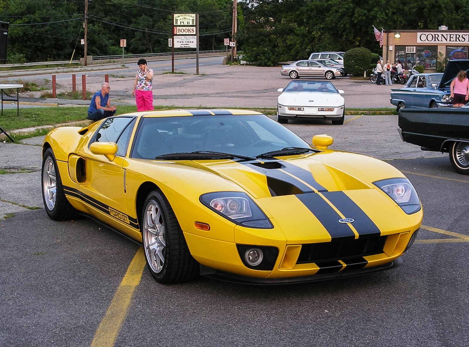 Yellow Ford GT street car with black racing stripes parked outdoors.