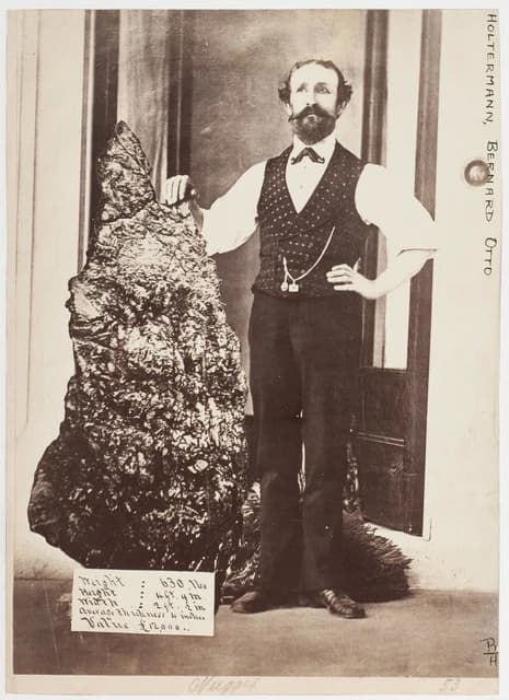 Bernhard Otto Holtermann stands next to a large, irregularly shaped gold specimen.