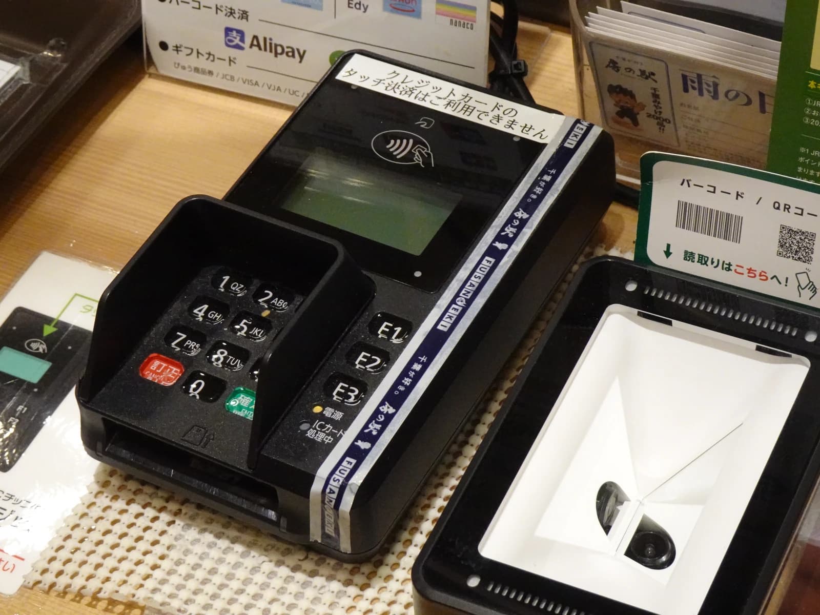 Payment terminals, including a credit card reader and a QR code scanner, on a counter.