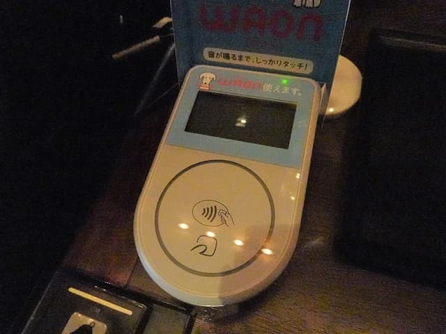 Close-up of a white contactless payment device with a screen and various symbols.