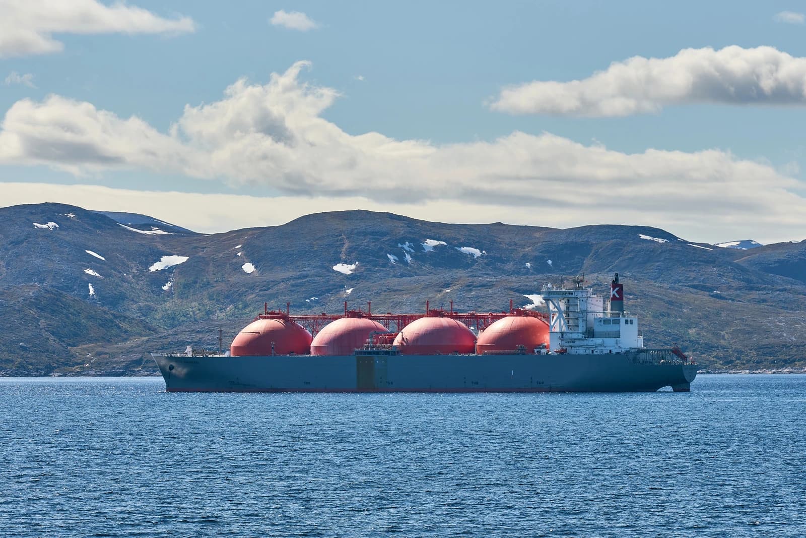 LNG carrier Arctic Discoverer sailing in a fjord with mountains in the background.
