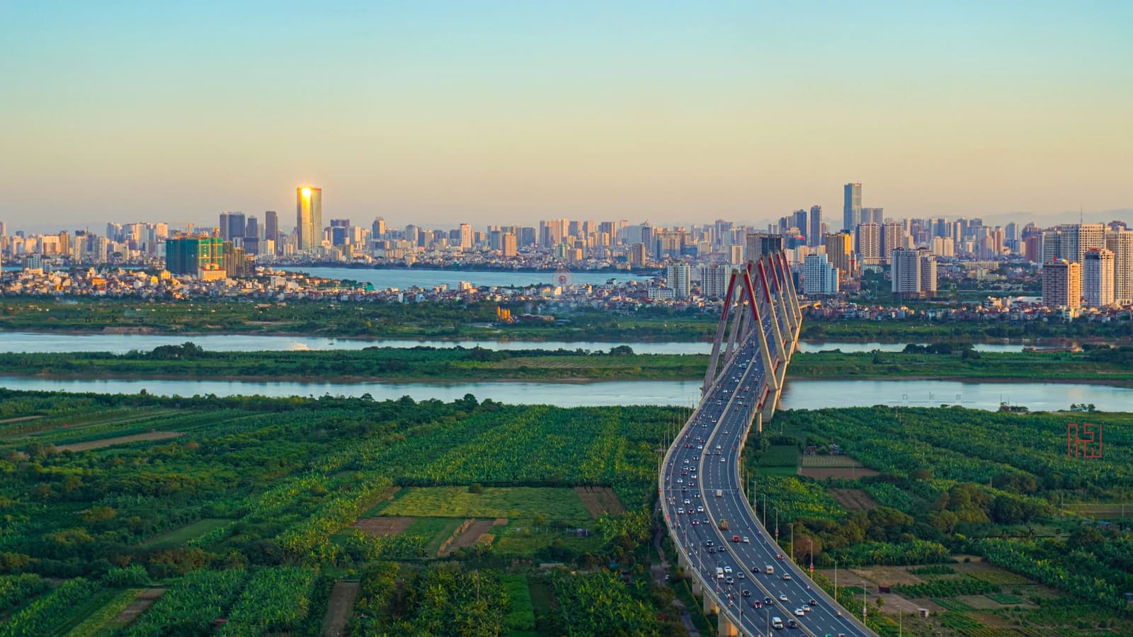 Aerial view of a bridge crossing a river with a city skyline in Hanoi, Vietnam.
