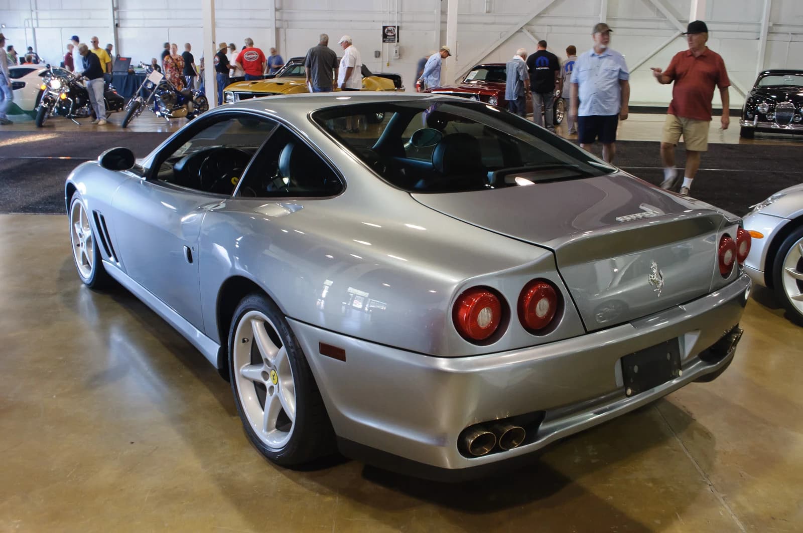 Silver 1998 Ferrari 550 Maranello on display at an indoor car show.