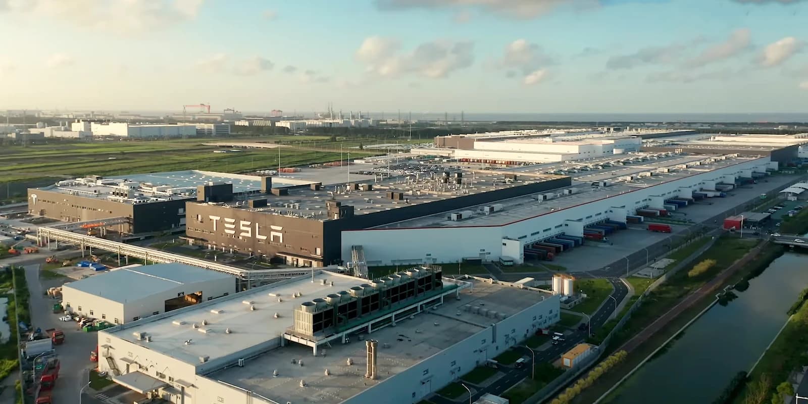 Aerial view of the Tesla Gigafactory Shanghai production facility with vehicles and docks.