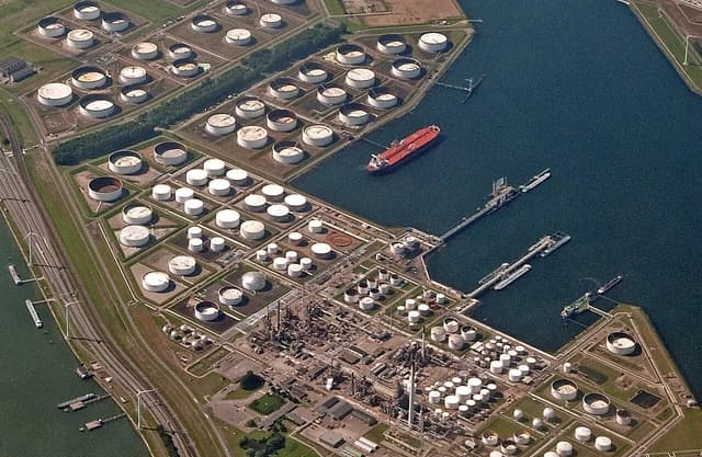 Aerial view of Europort in Rotterdam, Netherlands, showing numerous oil storage tanks and a large oil tanker in the harbor.