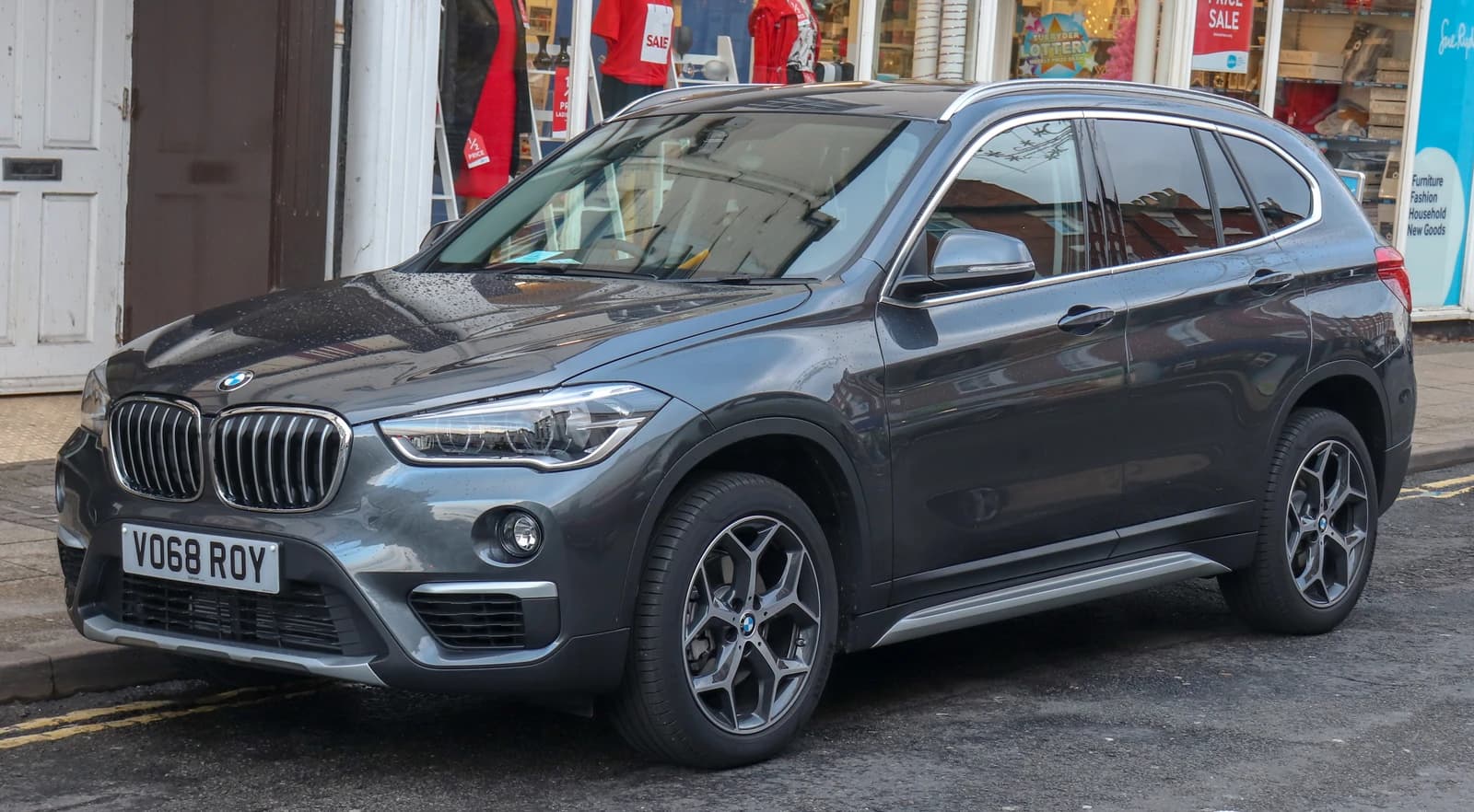 Gray 2018 BMW X1 sDrive18i xLine 1.5 parked on a street in front of shops.