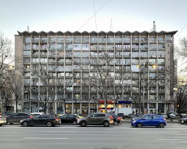 Apartment building in Bucharest, Romania, with bare trees and cars on a busy street.