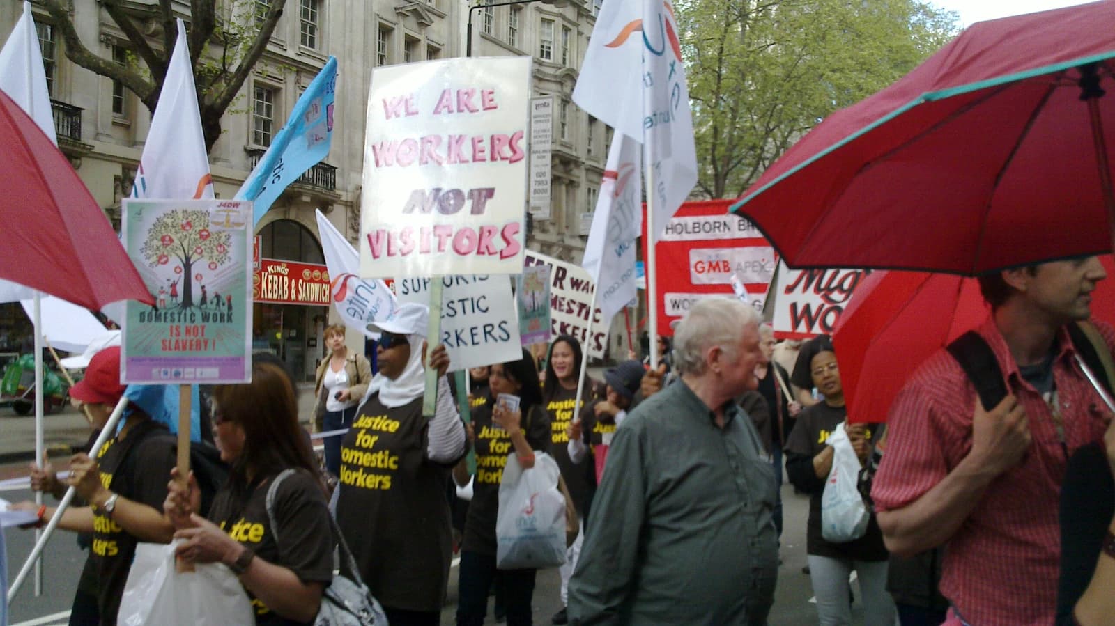 People carrying signs during a street demonstration in support of domestic workers' rights.