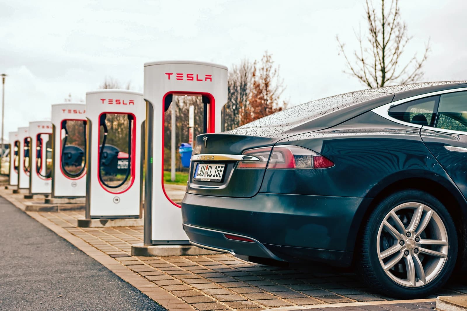 Rear view of a dark Tesla Model S parked at a row of Tesla Superchargers.