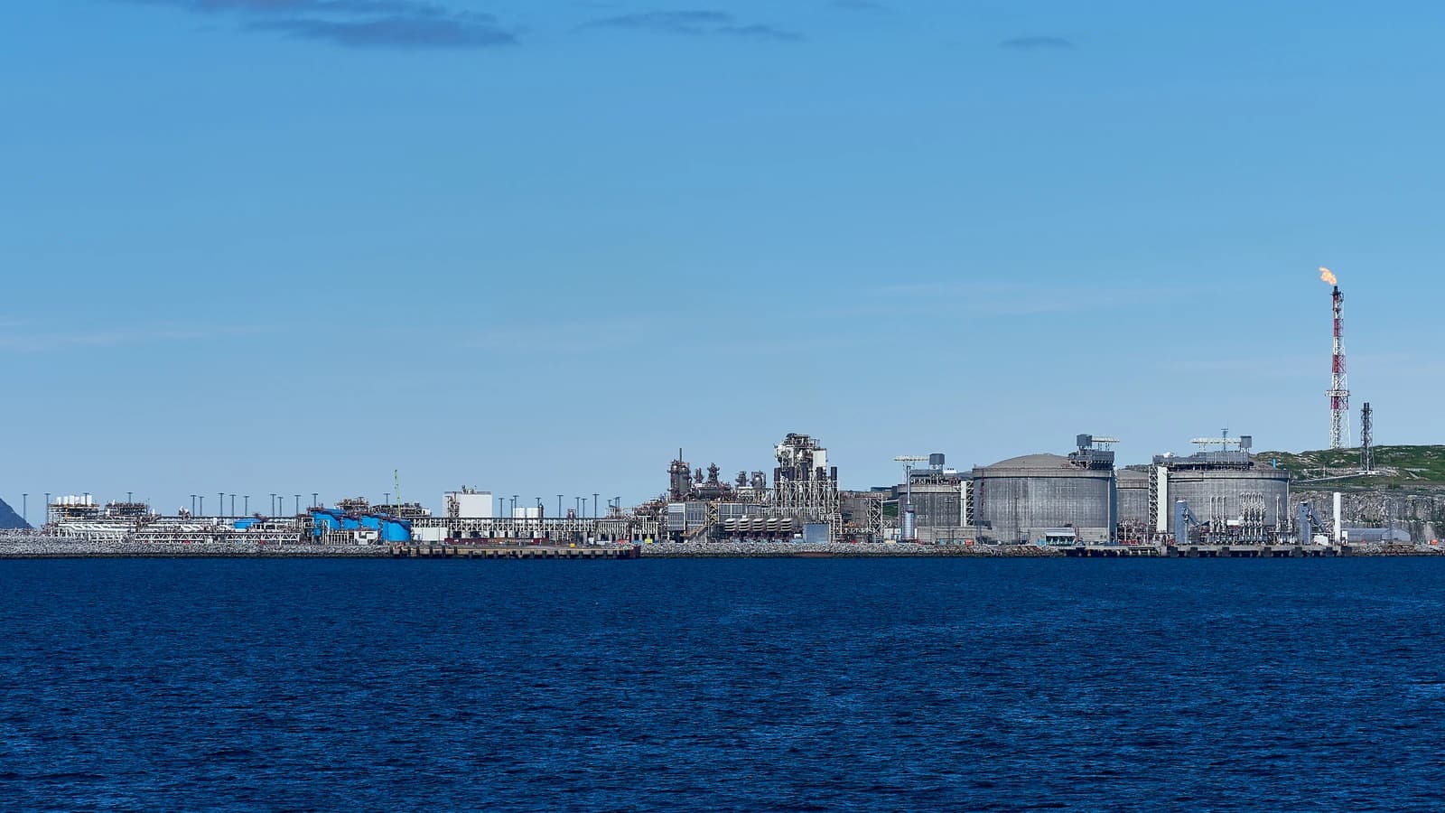 Melkøya LNG Terminal with large storage tanks and a burning flare stack.