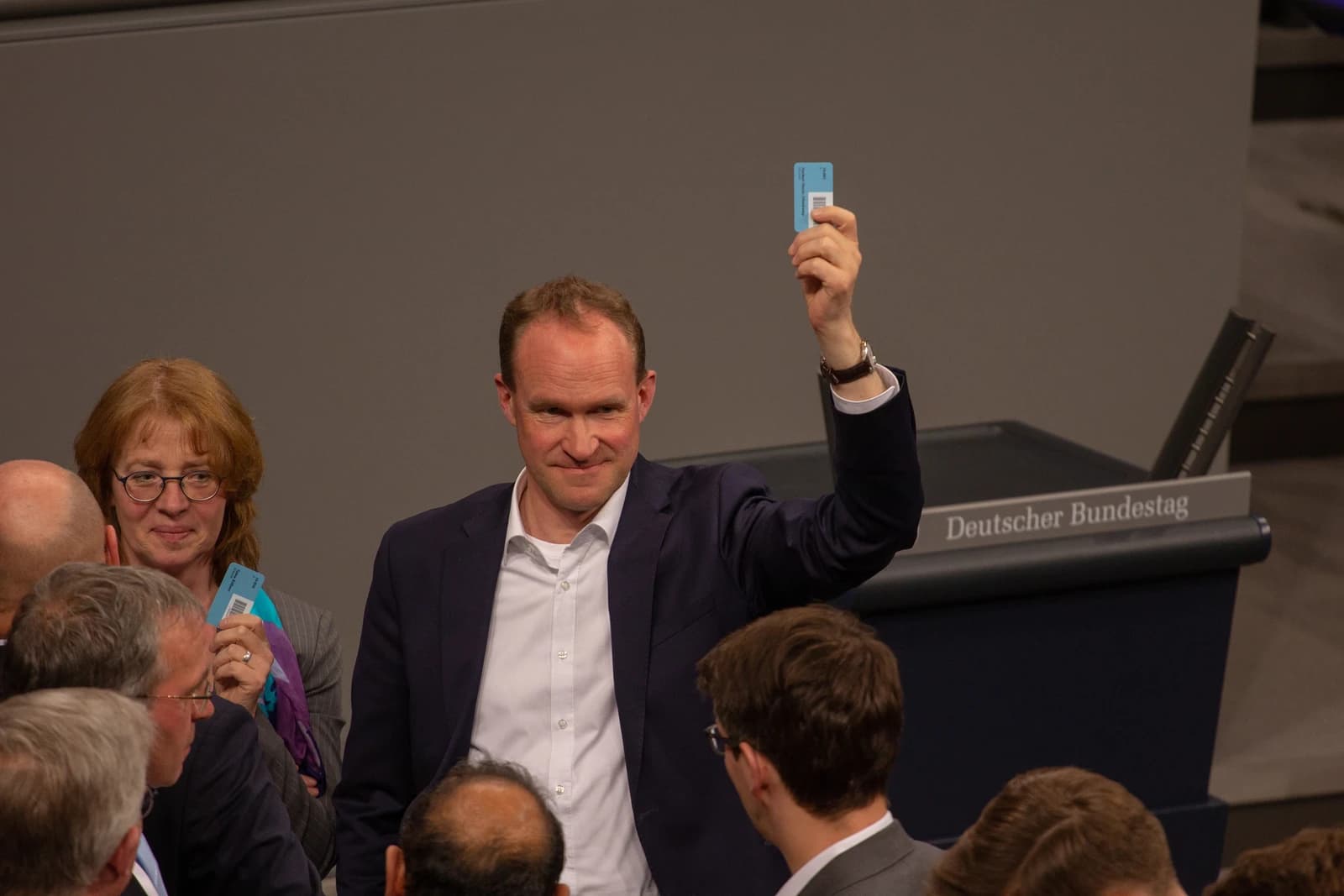 Man holding up a voting card in the German Bundestag chamber.